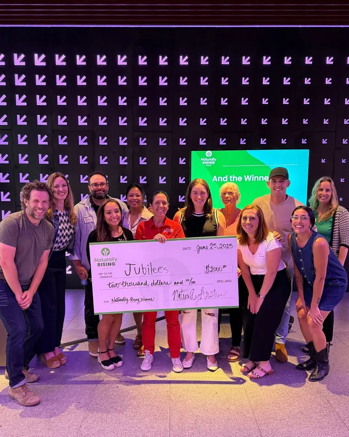 Pitch competition participants celebrating on stage with a prize check