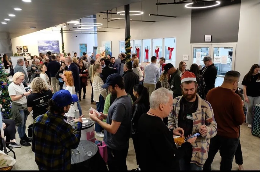 A busy community gathering with product tables and conversations